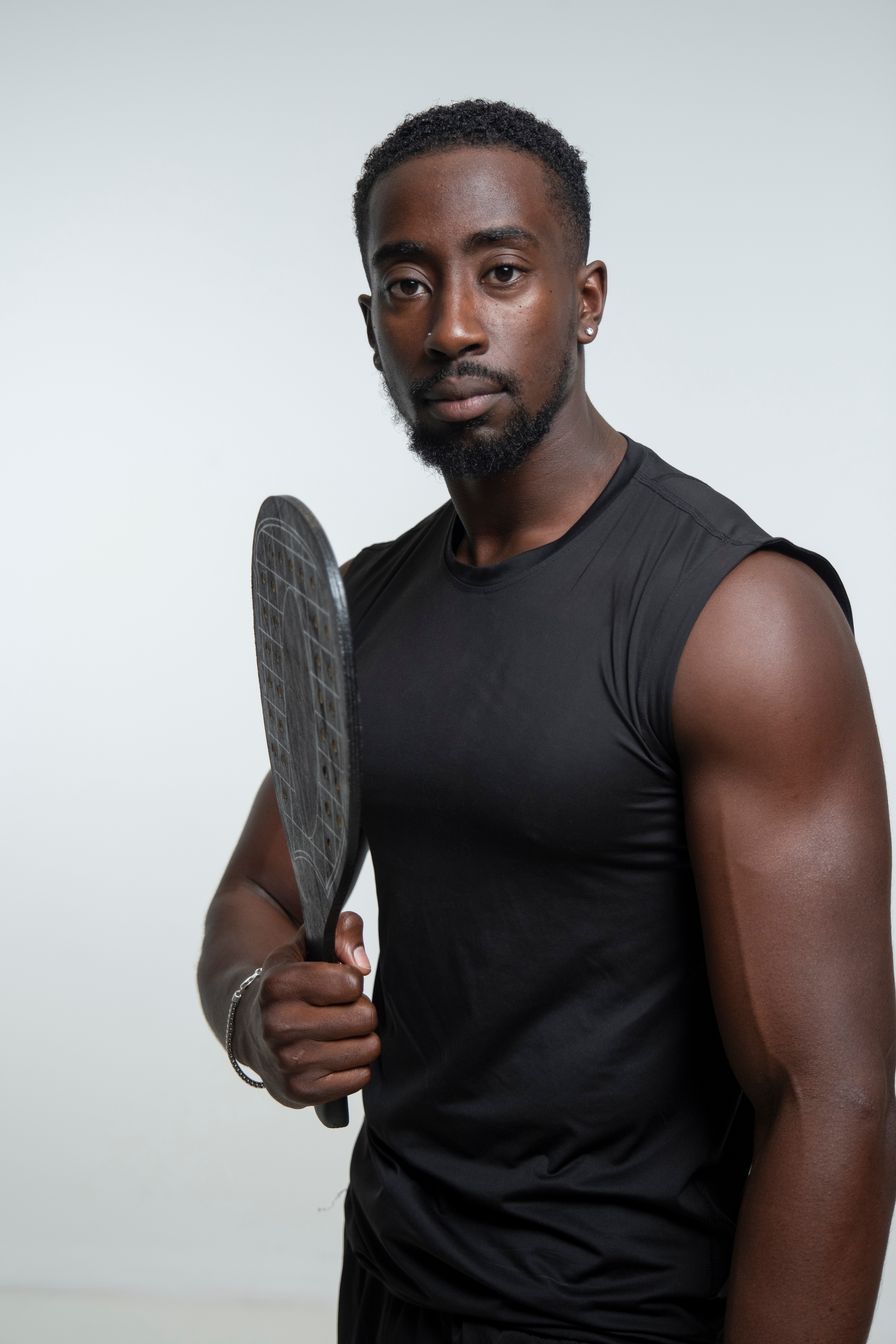 Portrait of pickleball coach Tim Kuss in a black sleeveless shirt holding a paddle