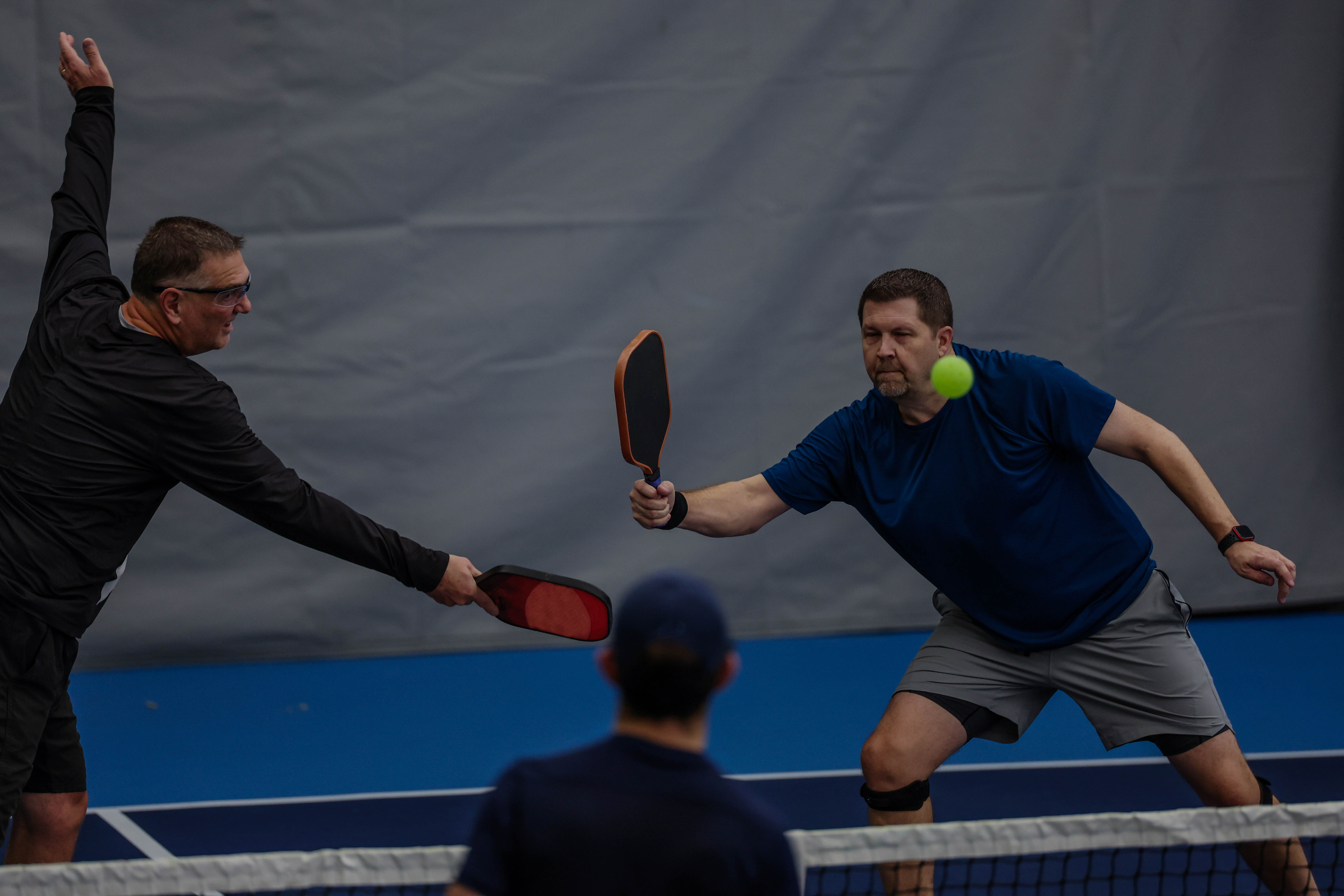 Two men playing a competitive game of indoor pickleball