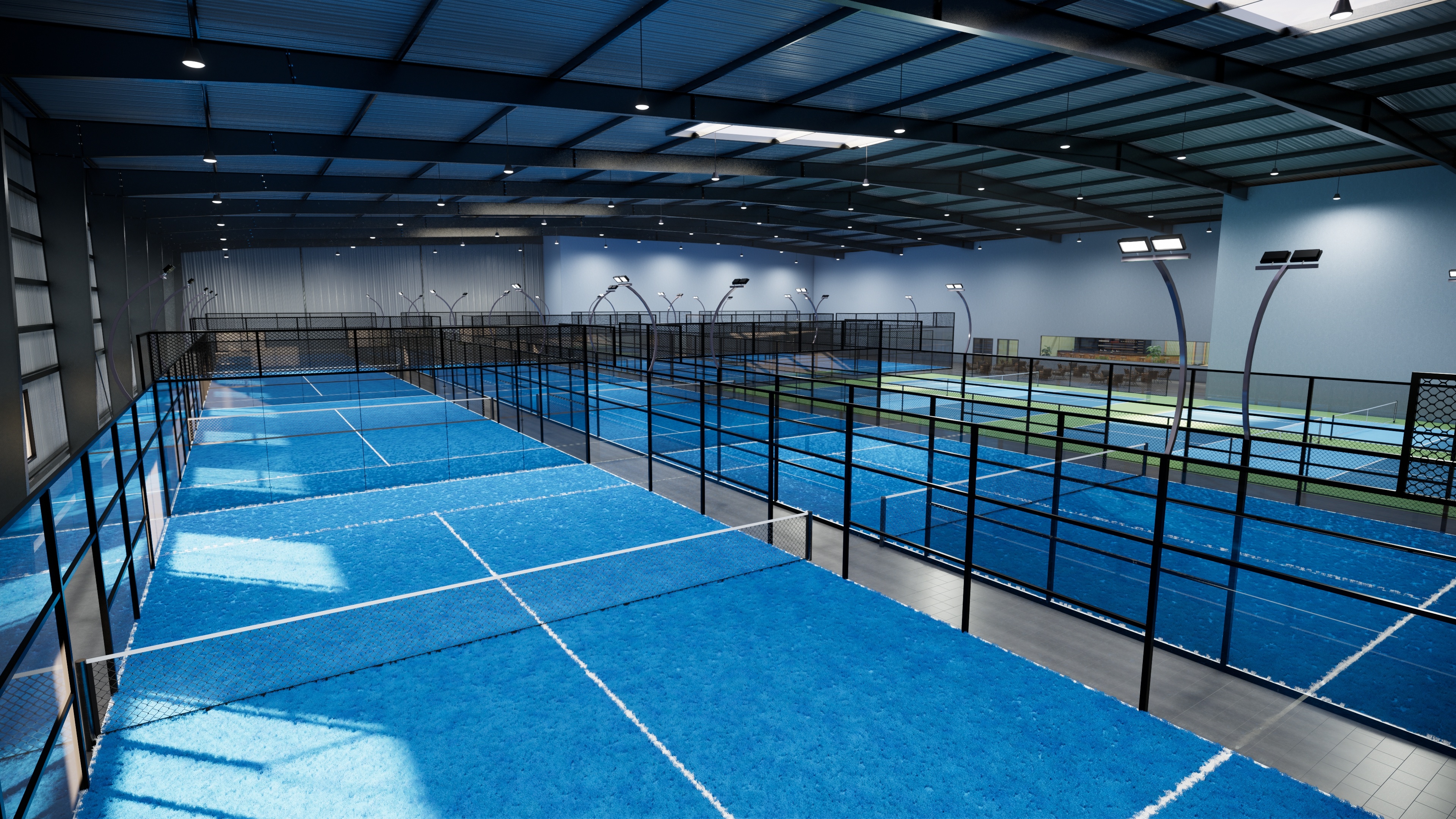 A large indoor pickleball facility featuring multiple blue courts with professional lighting
